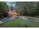 A gorgeous pool with a built-in jacuzzi, stone surround, waterfalls, patio, and backyard with lush landscaping at 205 Pine Lake Dr, Cumming, GA 30040