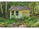 Backyard shed with natural siding with double doors and windows nestled among lush foliage at 205 Pine Lake Dr, Cumming, GA 30040