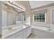Well lit bathroom with double vanity, large mirror, soaking tub and window at 65 Pecan Ln, Oxford, GA 30054