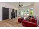 Bright sitting room featuring a bay window, hardwood floors, and red sofa with built-in shelves at 170 Autry Trl, Johns Creek, GA 30022