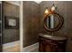 Elegant powder room with a decorative mirror, granite vanity, and stylish wallpaper at 170 Autry Trl, Johns Creek, GA 30022