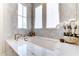 Elegant bathroom boasts a deep soaking tub beneath large windows, creating a serene and light-filled retreat at 4585 Ryker Rd, Cumming, GA 30041