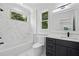 Bathroom with large window over tub, white marble tile, and modern vanity with black hardware at 4292 Sardis Church Rd, Buford, GA 30519
