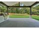 View of covered patio with an outdoor kitchen overlooking a large grassy backyard with trees at 4292 Sardis Church Rd, Buford, GA 30519