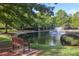 Community pond with fountain, mature trees, green grass, and a wooden bench at 3707 Vineyards Lake Nw Cir # 22, Kennesaw, GA 30144