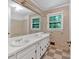 An outdated bathroom featuring double sinks, white cabinets, and checkered floors at 8587 Cumming Se Hwy, Canton, GA 30115