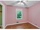 A bedroom featuring pink walls, wood floors, a ceiling fan and a window at 8587 Cumming Se Hwy, Canton, GA 30115