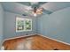 A bedroom featuring blue walls, wood floors, a ceiling fan and a window at 8587 Cumming Se Hwy, Canton, GA 30115