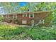 Rear view of brick home with overgrown lawn and foliage at 8587 Cumming Se Hwy, Canton, GA 30115