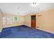 An outdated living room featuring wood-paneled walls, blue carpet, and a wood door at 8587 Cumming Se Hwy, Canton, GA 30115