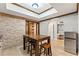 Basement dining area featuring a wood table, brick accent wall, and travertine tile flooring at 3560 Greenside Ct, Dacula, GA 30019