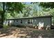 Rear view of the exterior of the home surrounded by mature trees and a small deck at 55 Forest Rd, Stockbridge, GA 30281