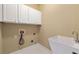 Well-lit laundry room featuring white cabinets, utility sink, and tile flooring at 917 Saints Ct, Marietta, GA 30068