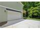 Two-car garage and extended driveway alongside green siding, providing convenient parking at 3159 Stonegate Sw Dr, Atlanta, GA 30331
