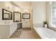 Bright bathroom featuring dual vanities, soaking tub, and modern lighting at 755 Creek Wind Ct, Johns Creek, GA 30097