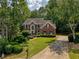 Traditional brick home featuring mature trees, lush landscaping, and a well-manicured lawn at 755 Creek Wind Ct, Johns Creek, GA 30097