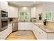 Bright kitchen featuring granite countertops, stainless steel appliances, white cabinetry, and hardwood floors at 755 Creek Wind Ct, Johns Creek, GA 30097