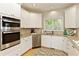 Bright kitchen featuring granite countertops, stainless steel appliances, white cabinetry, and hardwood floors at 755 Creek Wind Ct, Johns Creek, GA 30097