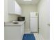 Small kitchenette with white appliances, cabinets, and vinyl flooring at 755 Creek Wind Ct, Johns Creek, GA 30097