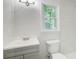 Bathroom with modern vanity, toilet, and shower with marble-look tiles, illuminated by a window at 104 Southfork Dr, Woodstock, GA 30189