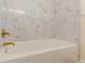 Bright bathroom featuring a soaking tub with gold fixtures and marble-style tiling at 1885 N Druid Hills Ne Rd, Atlanta, GA 30319