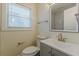 Bathroom with gray vanity, toilet, window with blinds, and framed mirror over gold faucet at 1885 N Druid Hills Ne Rd, Atlanta, GA 30319