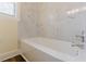 Clean bathroom featuring a tub with white marble tiling, light yellow walls, and vinyl wood flooring at 1885 N Druid Hills Ne Rd, Atlanta, GA 30319