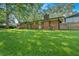 View of the back of the house, displaying its brick exterior, chimney, and a large, green lawn at 6600 N Beulah Rd, Lithia Springs, GA 30122