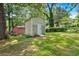 Backyard view with a white and grey storage shed on a lush, green lot at 6600 N Beulah Rd, Lithia Springs, GA 30122