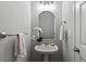 Compact powder room featuring a pedestal sink, arched mirror, and elegant lighting at 161 Forestview Dr, Suwanee, GA 30024
