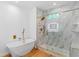 Luxurious bathroom featuring a soaking tub, and a glass-enclosed shower with gold fixtures and marble tile at 1835 Taylor Ave, East Point, GA 30344