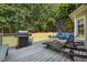 A well appointed back deck with comfortable outdoor seating, a grill, and lush tree surround at 3845 Overlake Dr, Cumming, GA 30041