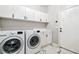Bright laundry room featuring modern washer and dryer, white cabinetry, and stylish marble flooring at 3845 Overlake Dr, Cumming, GA 30041