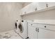 Bright laundry room with front loading machines, white cabinets, and marble tile flooring at 3845 Overlake Dr, Cumming, GA 30041