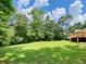 Expansive green backyard featuring a lush lawn, mature trees, and a charming wooden deck at 7680 Banks Mill Road Rd, Douglasville, GA 30135