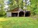 Rustic barn with weathered wood, open doorway and a gate, surrounded by a lush green lawn and trees at 7680 Banks Mill Road Rd, Douglasville, GA 30135