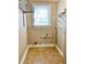 A compact laundry room features neutral walls, tile flooring, and a window with blinds for natural light at 7680 Banks Mill Road Rd, Douglasville, GA 30135