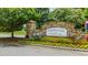 Stone entrance sign for Northwoods at Mirror Lake, surrounded by colorful flowers and greenery at 114 Crooked Lake Park, Villa Rica, GA 30180