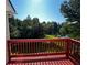 Spacious wood deck featuring red railings and views of the lush surrounding greenery and calm water at 2550 Lynshire Ln, Snellville, GA 30078