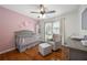 Bedroom with pink accent wall, hardwood floors, a ceiling fan, and a gray crib at 2775 Harper Ferry Dr, Lawrenceville, GA 30044