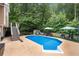 Backyard featuring an in-ground pool and lounge seating with an array of trees in the background at 2775 Harper Ferry Dr, Lawrenceville, GA 30044