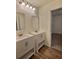 Bathroom featuring double vanity with white cabinets, mirrors and wood-look flooring at 1081 Hardin Street Sw St, Conyers, GA 30012