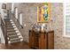 Stylish staircase with brick wall, wine rack, and modern art, creating an inviting and sophisticated entryway at 506 Broadview Ne Pl, Atlanta, GA 30324