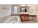Bathroom features a soaking tub with decorative tile surround, vanity and unique window feature at 5485 Sandstone Ct, Cumming, GA 30040