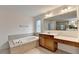 Bright bathroom featuring a large soaking tub, wooden vanity with sink, and a decorative window at 5485 Sandstone Ct, Cumming, GA 30040