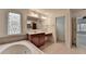 This bathroom features a soaking tub with tile surround, single vanity and unique window at 5485 Sandstone Ct, Cumming, GA 30040