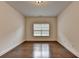 Empty bedroom featuring wood floors, a window, white walls, and a neutral color scheme at 5485 Sandstone Ct, Cumming, GA 30040
