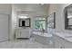 Bright bathroom featuring a soaking tub with a golden faucet, marble floors, and white cabinets at 1723 Woodbow Path, Dacula, GA 30019