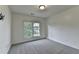 A simple carpeted bedroom features a window, ideal for creating a cozy and personalized retreat at 1723 Woodbow Path, Dacula, GA 30019