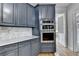 Close-up of a kitchen featuring dark blue cabinets, stainless steel oven, marble countertops, and hardwood flooring at 1723 Woodbow Path, Dacula, GA 30019